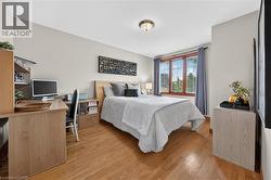 Hardwood flooring, neutral wall tones, three-panel window, flush mount ceiling fixture, and built-in desk with shelving - 