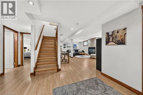 Wood-finish flooring throughout, with a wood staircase and handrail, recessed lighting, and a stone-clad fireplace - 52 Archwood Crescent, Cambridge, ON 