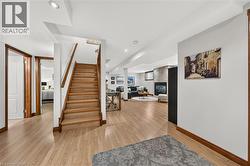 Wood-finish flooring throughout, with a wood staircase and handrail, recessed lighting, and a stone-clad fireplace - 