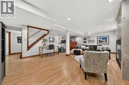 Recessed lighting, wood-finish flooring, a wood-trimmed staircase, a built-in wet bar, and a fireplace with a stone surround - 52 Archwood Crescent, Cambridge, ON 