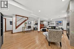 Recessed lighting, wood-finish flooring, a wood-trimmed staircase, a built-in wet bar, and a fireplace with a stone surround - 