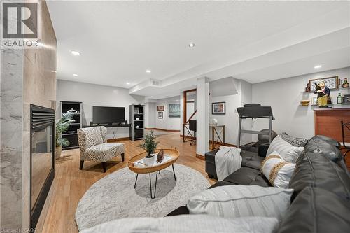 Recessed lighting illuminates this room, featuring light wood-finish flooring and a built-in fireplace with a stone-finish surround - 52 Archwood Crescent, Cambridge, ON 