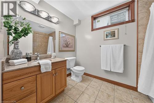 Wood-finish vanity with a light-toned countertop, large mirror, and three-light fixture - 52 Archwood Crescent, Cambridge, ON 