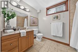 Wood-finish vanity with a light-toned countertop, large mirror, and three-light fixture - 