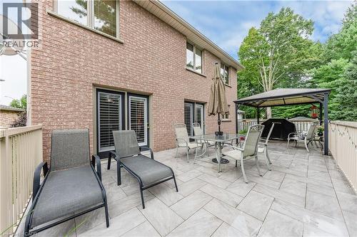 Expansive outdoor patio featuring light-toned large format tile, brick exterior, and a permanent covered gazebo structure - 52 Archwood Crescent, Cambridge, ON 