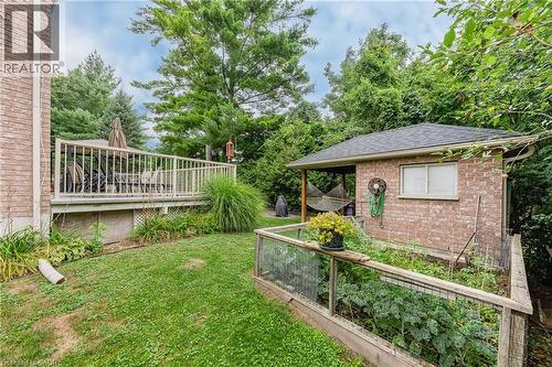 Expansive backyard featuring a raised garden bed, a brick shed with an overhang, and a wood deck with railings - 52 Archwood Crescent, Cambridge, ON 