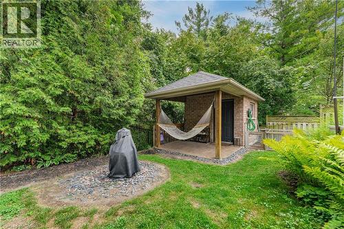 Manicured lawn with mature perimeter landscaping, brick shed with covered patio, and a privacy fence - 52 Archwood Crescent, Cambridge, ON 