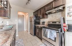 Kitchen with backsplash, appliances with stainless steel finishes, under cabinet range hood, and dark brown cabinetry - 
