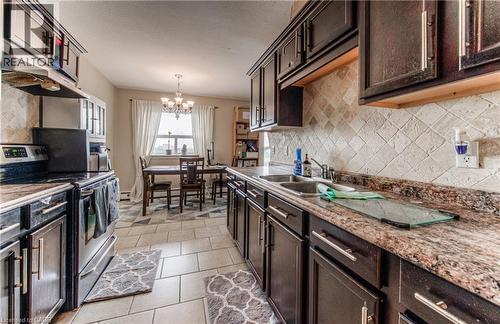 Kitchen featuring stainless steel range with electric stovetop, dark brown cabinets, a chandelier, and a textured ceiling - 283 Fairway Road N Unit# 501, Kitchener, ON 