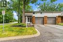 Brick and siding exterior featuring two garage doors, a paved driveway, and established front landscaping - 1270 Gainsborough Drive Unit# 61, Oakville, ON 