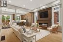 Open-concept living space with wood-finish flooring, a contemporary linear fireplace with slatted wood surround, and recessed lighting - 279 Hess Street S, Hamilton, ON 