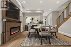 Wood-finish flooring, recessed lighting, built-in electric fireplace, wood-slat feature wall, and a staircase with wood treads and black metal balusters - 
