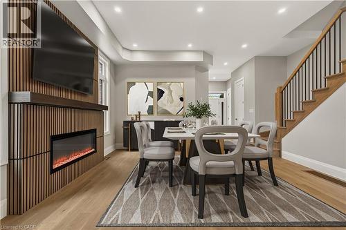 Wood-finish flooring, recessed lighting, built-in electric fireplace, wood-slat feature wall, and a staircase with wood treads and black metal balusters - 279 Hess Street S, Hamilton, ON 