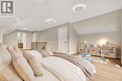 Sloped ceilings with recessed lighting, wood-finish flooring, white paneled door, and a wooden handrail with metal spindles - 279 Hess Street S, Hamilton, ON 