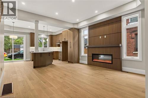 Spacious open-concept layout with light wood-finish flooring, recessed lighting, and a linear electric fireplace with a slatted wood surround - 279 Hess Street S, Hamilton, ON 