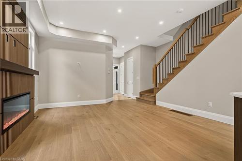 Wood-finish flooring, staircase with metal balusters, built-in fireplace with a wood-slat surround, recessed lighting, and a tray ceiling - 279 Hess Street S, Hamilton, ON 