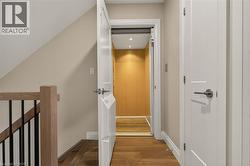 Hardwood flooring, wood-finish stair railing with black spindles, light-colored walls, white trim, and a built-in elevator - 