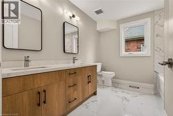 Dual sink vanity with wood-finish cabinetry, white countertop, and contemporary black-framed mirrors - 