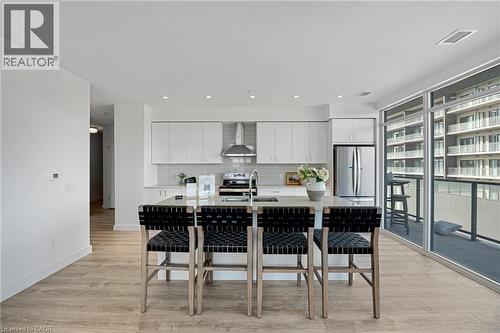 Kitchen with white cabinets, decorative backsplash, light wood-style flooring, appliances with stainless steel finishes, and recessed lighting - 50 Grand Avenue S Unit# 801, Cambridge, ON 