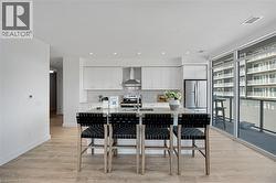 Kitchen with white cabinets, decorative backsplash, light wood-style flooring, appliances with stainless steel finishes, and recessed lighting - 