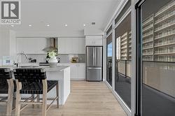 Kitchen featuring white cabinets, a kitchen bar, freestanding refrigerator, decorative backsplash, and recessed lighting - 