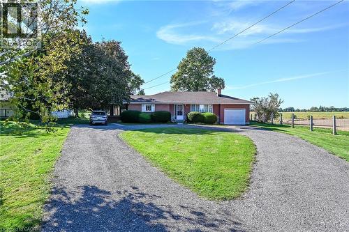 Red brick exterior with white trim, attached single-car garage, and a gravel driveway - 799 Highway 6, Caledonia, ON 