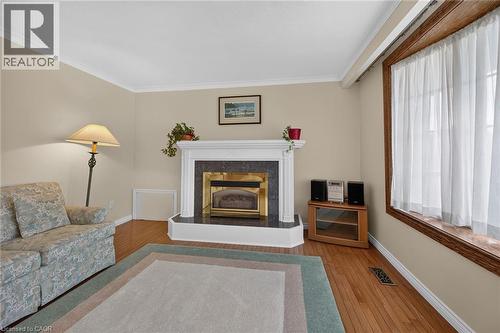 Hardwood flooring, crown molding, white fireplace mantel, dark stone fireplace surround, and a large window with wood trim - 799 Highway 6, Caledonia, ON 