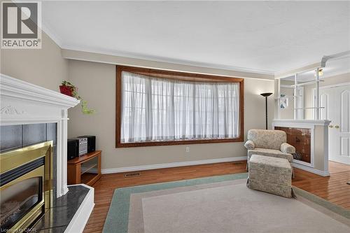 Wood-finish flooring, white crown molding, bay window with wood trim, white fireplace with dark hearth, and a built-in room divider - 799 Highway 6, Caledonia, ON 