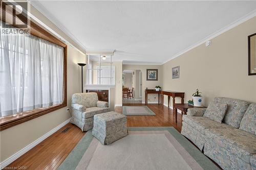 Hardwood flooring throughout, featuring a large window with wood trim, crown molding, and neutral wall tones - 799 Highway 6, Caledonia, ON 