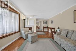 Hardwood flooring throughout, featuring a large window with wood trim, crown molding, and neutral wall tones - 
