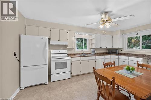 Kitchen featuring white appliances, a ceiling fan, white cabinetry, and a double basin sink - 799 Highway 6, Caledonia, ON 