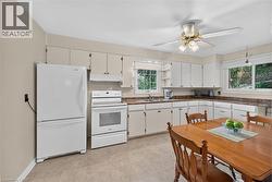 Kitchen featuring white appliances, a ceiling fan, white cabinetry, and a double basin sink - 