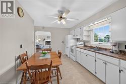 Kitchen featuring white cabinetry, a double basin sink, white appliances, and a ceiling fan - 
