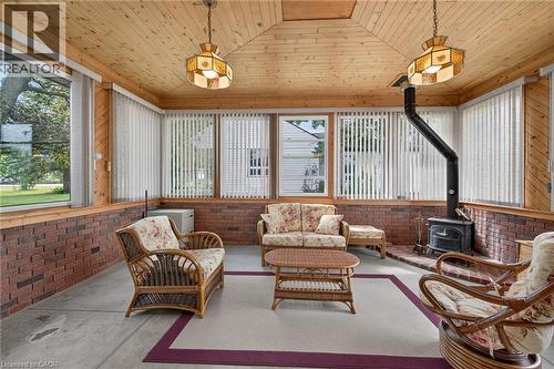 Wood-paneled ceiling with exposed beams, brick accent walls, and a freestanding wood-burning stove - 799 Highway 6, Caledonia, ON 