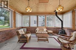 Wood-paneled ceiling with exposed beams, brick accent walls, and a freestanding wood-burning stove - 