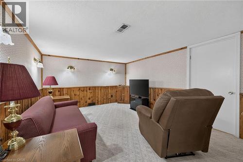Light-colored carpeted flooring, wood paneling, wall-mounted sconces, and a white interior door - 799 Highway 6, Caledonia, ON 