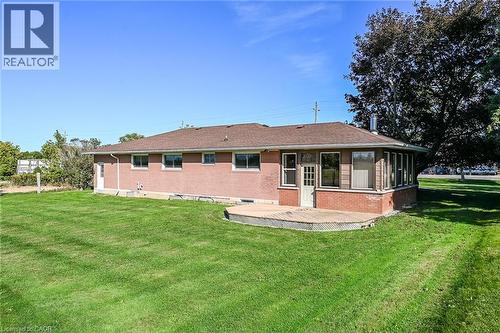 Brick exterior featuring a sunroom, a wooden deck, and a spacious lawn - 799 Highway 6, Caledonia, ON 