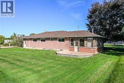 Brick exterior featuring a sunroom, a wooden deck, and a spacious lawn - 