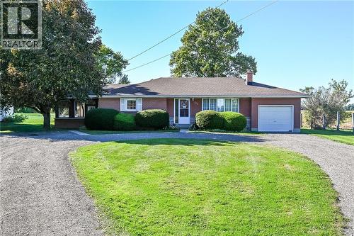 Single-story residence featuring a brick exterior, attached garage, and gravel driveway - 799 Highway 6, Caledonia, ON 