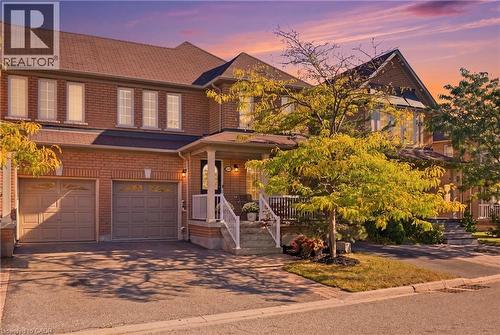 Brick exterior with two-car garage, covered porch, and paved driveway - 2409 Postmaster Drive, Oakville, ON 