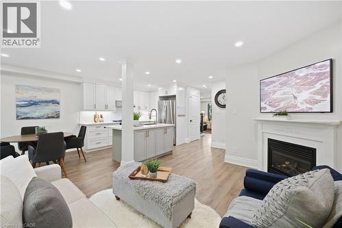 Open-concept living space featuring wood-finish flooring, recessed lighting, and a white fireplace mantel - 2409 Postmaster Drive, Oakville, ON 