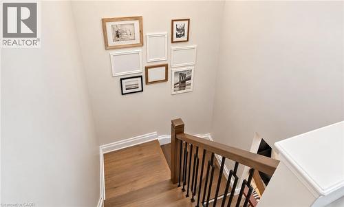 Hardwood stairs with coordinating wood-finish handrail and black metal balusters - 2409 Postmaster Drive, Oakville, ON 