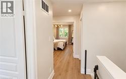 Hallway with light wood-finish flooring, white trim, and neutral wall paint - 