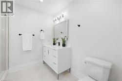 White vanity with integrated sink, matte black faucet, wall-mounted lighting fixture, framed mirror, and glass shower enclosure - 