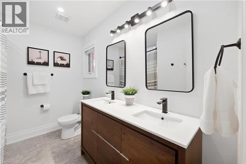 Dual vanity with integrated sinks, dark wood-finish cabinetry, matte black fixtures, and framed mirrors - 2409 Postmaster Drive, Oakville, ON 