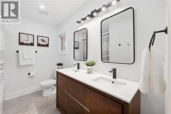 Dual vanity with integrated sinks, dark wood-finish cabinetry, matte black fixtures, and framed mirrors - 