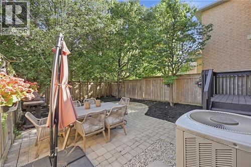 Paved patio area, wood fencing, mature trees, dark wood deck, and brick exterior - 2409 Postmaster Drive, Oakville, ON 