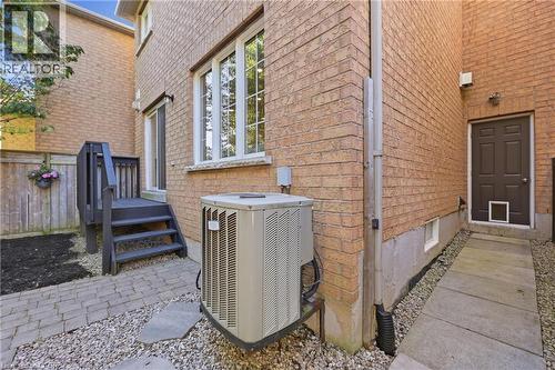 Brick exterior with a dark-stained wood deck, white-framed windows, and a paver stone patio - 2409 Postmaster Drive, Oakville, ON 