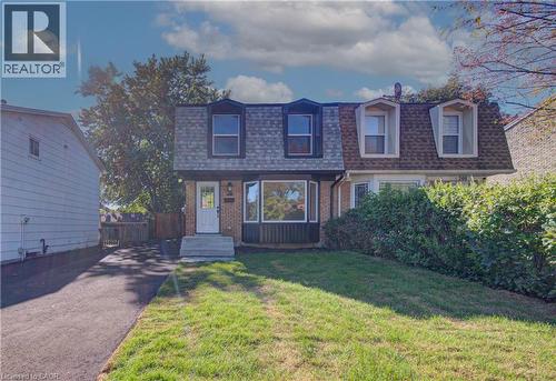 Brick exterior featuring a mansard roof, front lawn, and paved driveway - 210 Ferguson Avenue, Cambridge, ON 