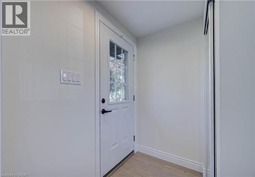 White paneled door with glass inserts, black hardware, and light wood-finish flooring - 210 Ferguson Avenue, Cambridge, ON 